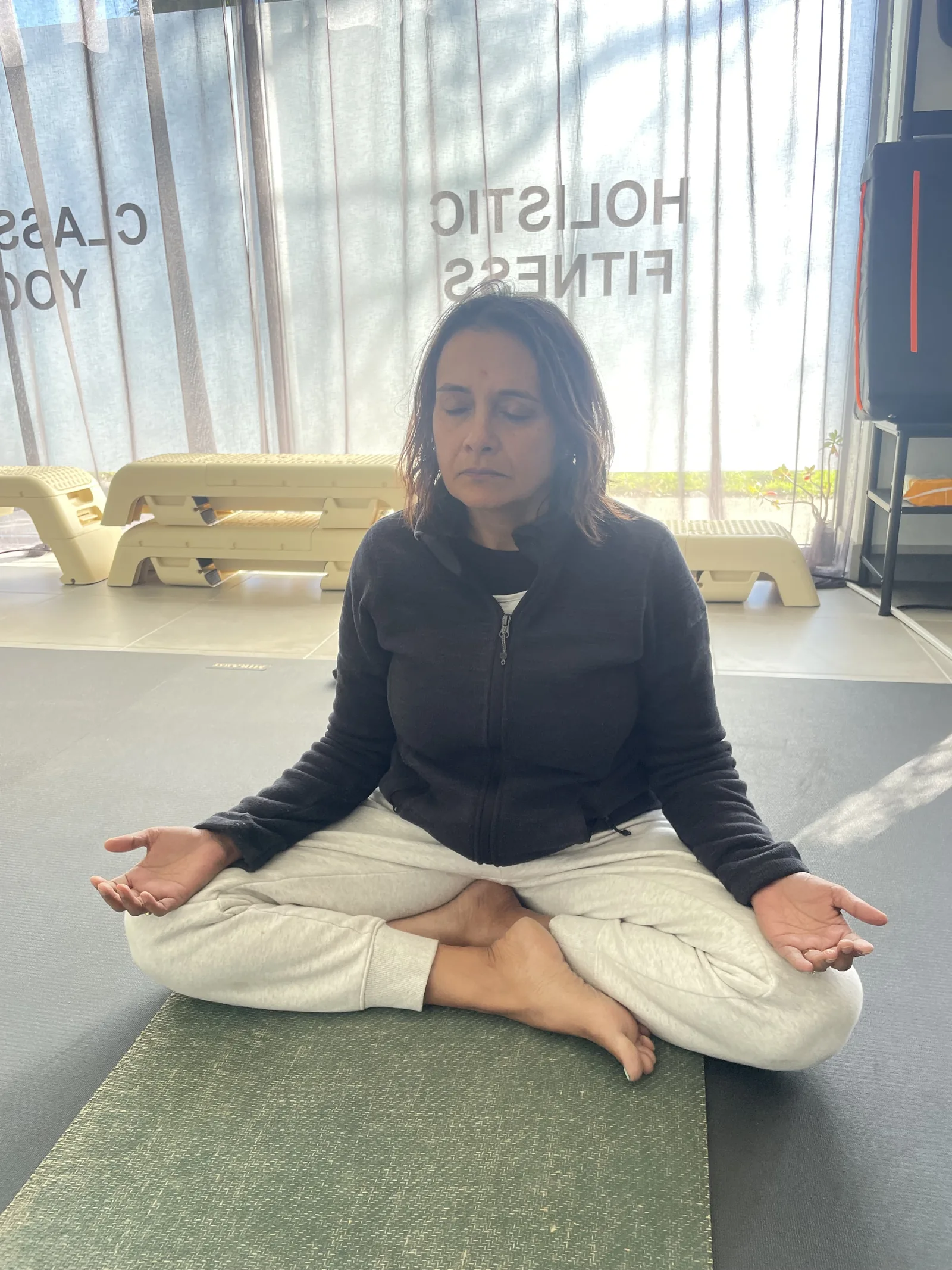Person seated cross-legged in quiet meditation at the Adiyoga studio in Earlwood