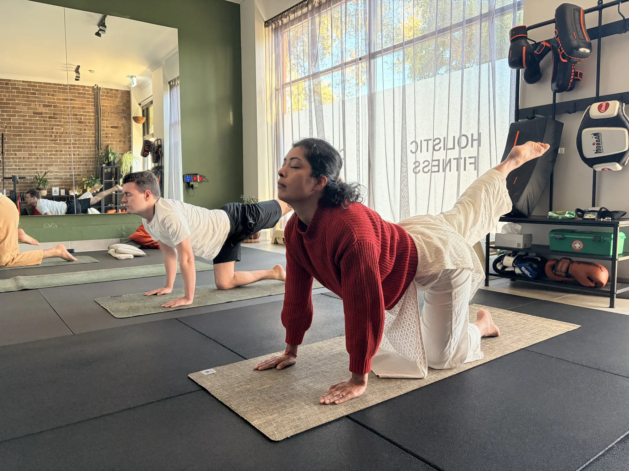 Two students holding a strong standing pose during a classical yoga session at Adiyoga in Earlwood