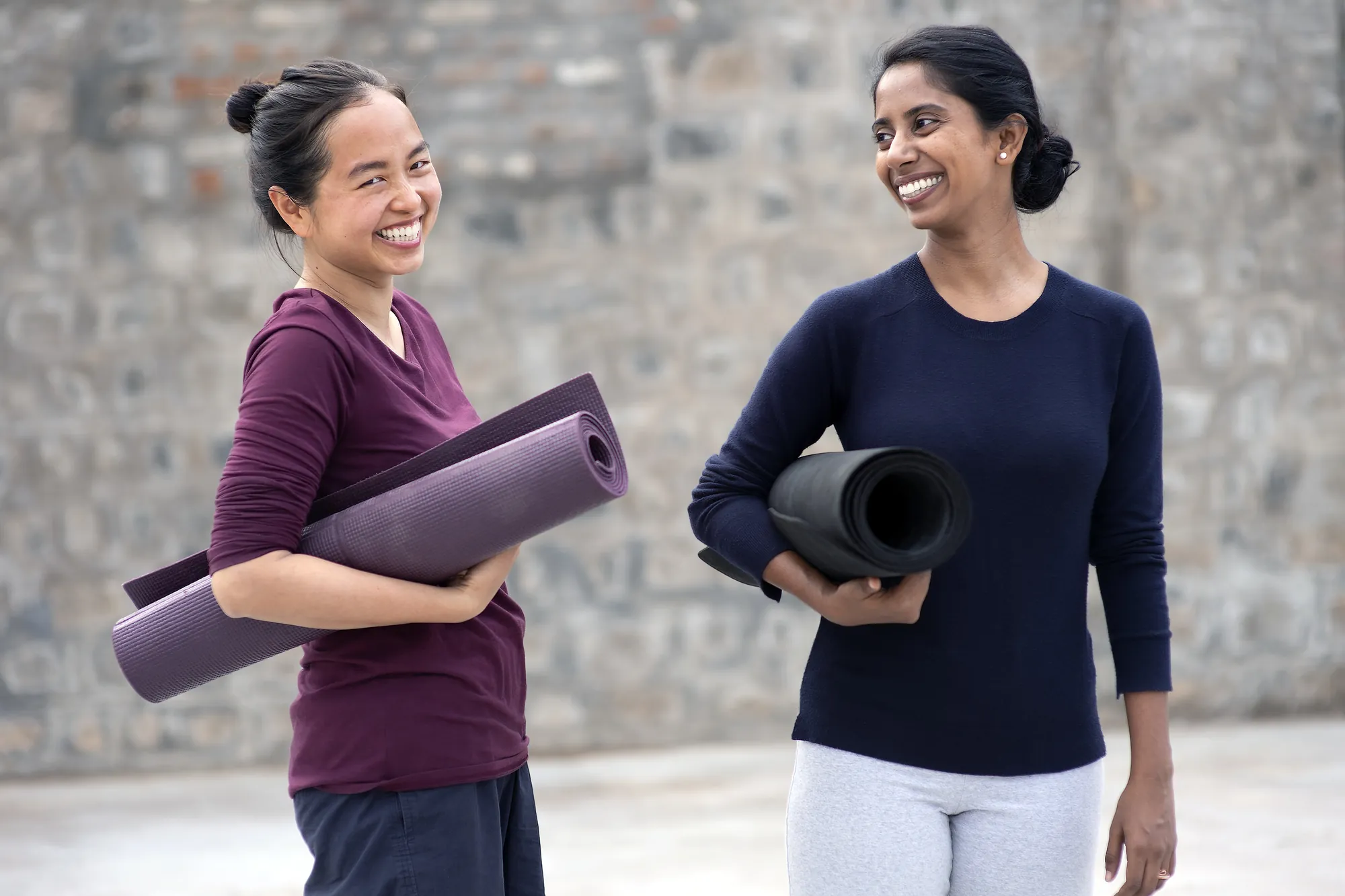 Two Adiyoga teachers smiling together holding their yoga mats at the studio in Earlwood